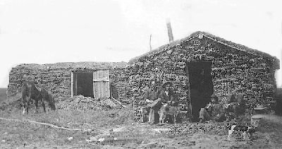 Settlers in front of a prairie sod house