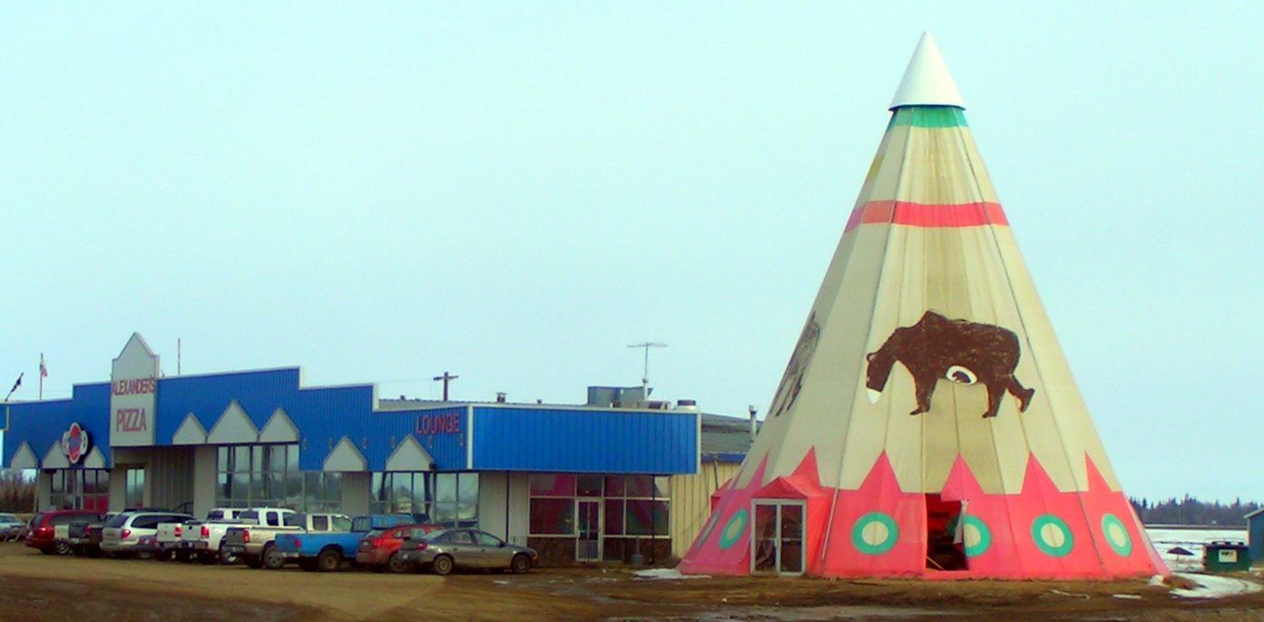 The large painted tipi roadside landmark at Rycroft, Alberta, beside a highway building